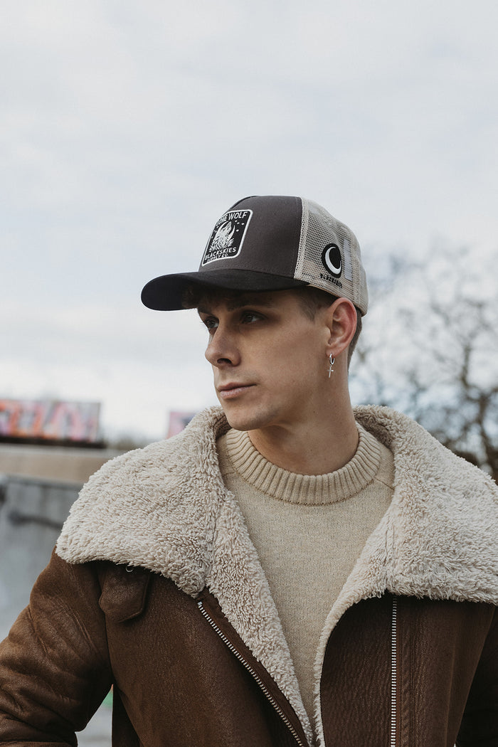 Man wearing a cap and brown jacket with a blurred background