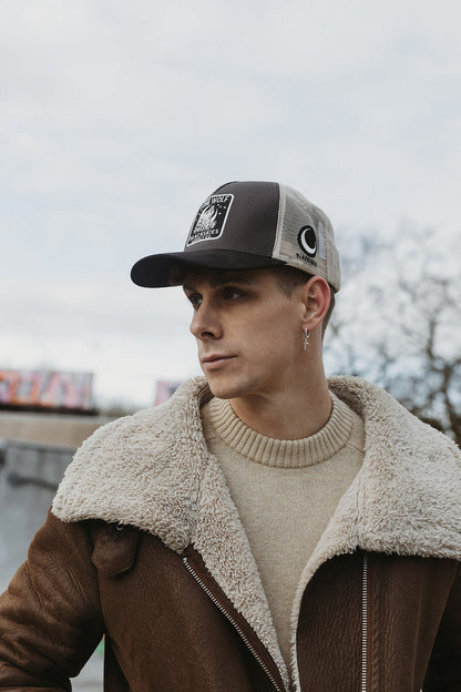 Man wearing a cap and brown jacket with a blurred background